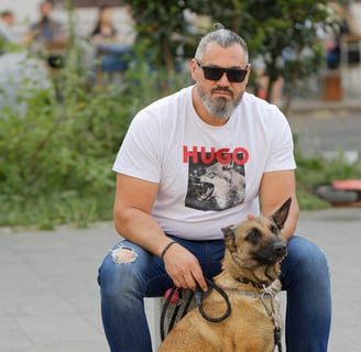 Business owner sitting with his dog Hugo who is also wearing a hugo the dog shirt