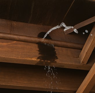 a broken pipe spouting water in a wooden ceiling