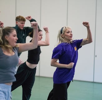 A group of dancers holding their arms up mid dance