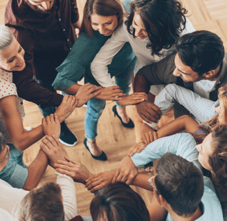 a group of people standing in a circle with their hands together