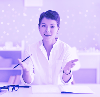 a woman in a white shirt and glasses sitting at a desk