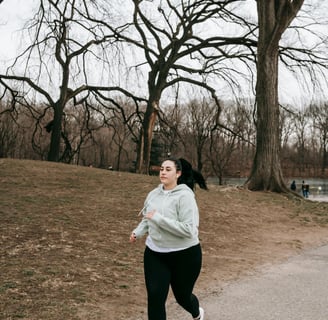 a woman in a gray hoodie running on a path