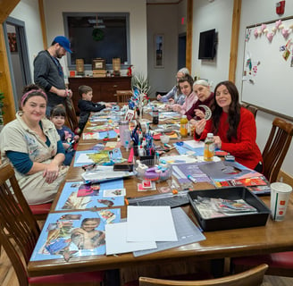 a group of adults and children sitting around a table making collages