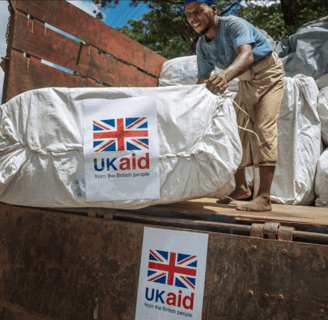 a man standing on a truck with a large pile of bags