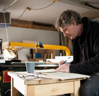 The artist in his studio. He is mid-fifties with unruly, wavy hair flecked with gray.