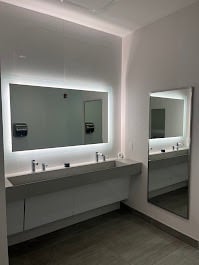 A mirror, sink, and faucets inside a modern bathroom.