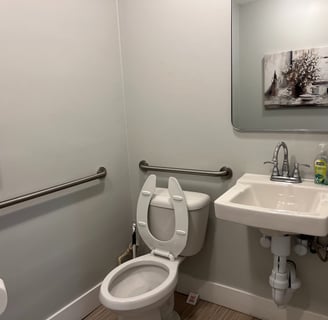 A toilet, sink, and mirror inside the bathroom of a business.