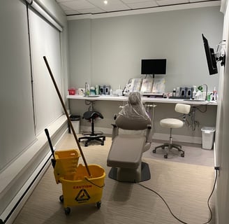 A dental office room with a chair in it and a mop in a bucket.