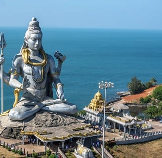 Lord Shiva statue with the background of blue sea, trees beside the status