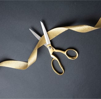 a pair of scissors cutting a gold ribbon