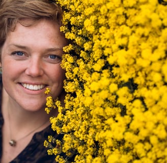 Billede af Gundas ansigt ved siden af et hav af gule blomster.
