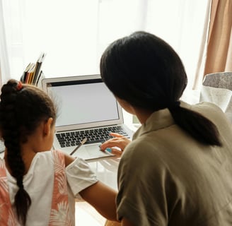a woman sitting at a table with a laptop computer
