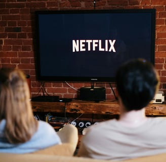 a man and woman sitting on a couch watching a tv