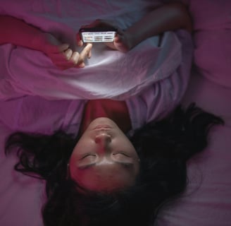 a woman laying on a bed with a cell phone