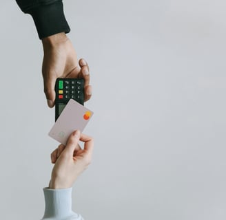 Person holding a credit card while making a payment with a card reader.