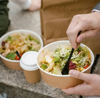 a person is eating a salad in a paper bag