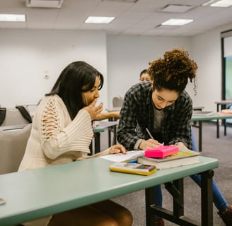 two woman sitting at desks in a classroom
