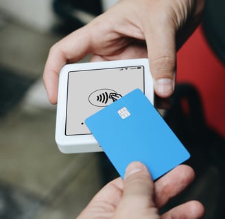 Person making a contactless payment with a blue card on a mobile payment terminal.