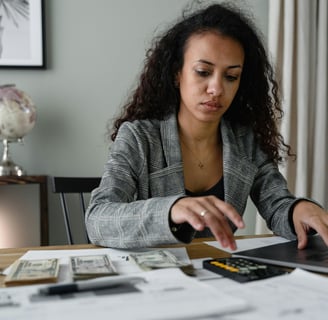 a woman sitting at a desk with a laptop and a calculator