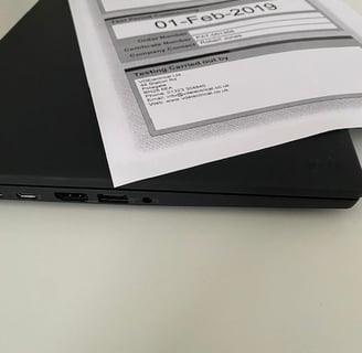 a laptop computer sitting on a desk with a paper document
