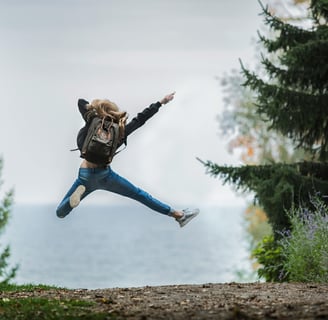 a woman jumping in the air with her hands up in the air