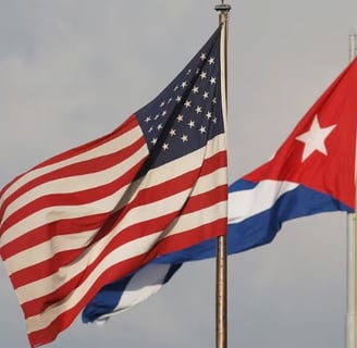 two flags are flying in the sky. USA, Cuba,