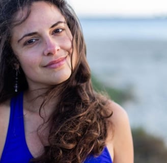 a woman in a blue tank top and earrings