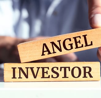 person holding wooden blocks that read "angel" "investor"
