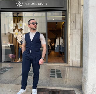 a man in a vest and sunglasses standing in front of a Duemme store