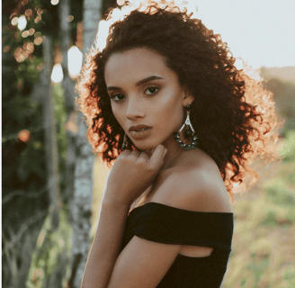 a woman with curly hair and earrings on her neck