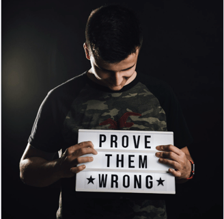 a man holding a sign that says prove them wrong