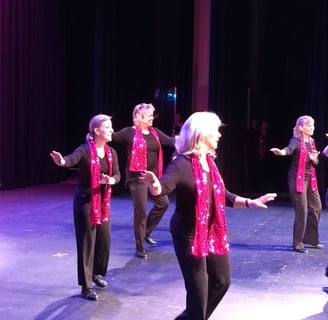 a group of women tap dancers in pink and black outfits on stage