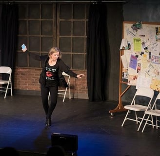 a woman Amy Cave in a black top tap dancing on stage in a play.