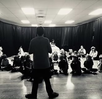 a youth director standing in front of a group of actors getting notes before the show.