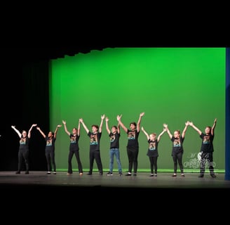 a group of kids in a musical theatre class dancing on a stage