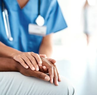 A nurse gently holds a patient's hand, providing comfort and support in a healthcare setting.