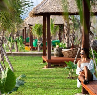 a woman sitting on a bench in a tropical setting