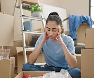 Stressed woman surrounded by moving boxes before a cleanout by West Linn Junk Removal