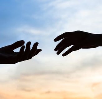 two hands reaching out to each other in front of a sunset