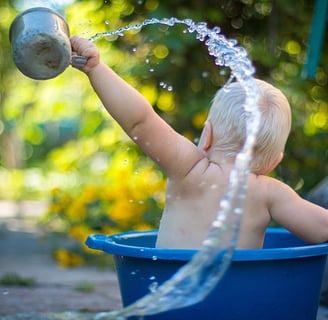 Picture of a baby in small tub having a wonderful time throwing water everywhere