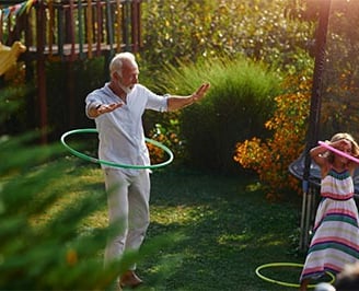 Grandad and his little granddaughter doing hula hooping in the garden