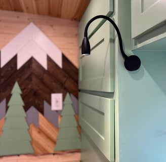 custom cabinetry inside schoolie bus featuring handmade mountain background for headboard of bed