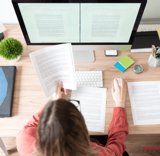 a woman sitting at a desk with a book and a computer