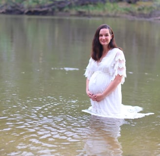 a pregnant woman in a white dress standing in the water