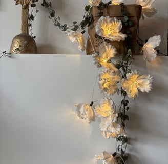 a cross on a white wall with flowers and a cross