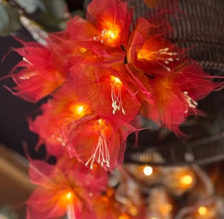 a bird cage with red flowers and a bird in the background