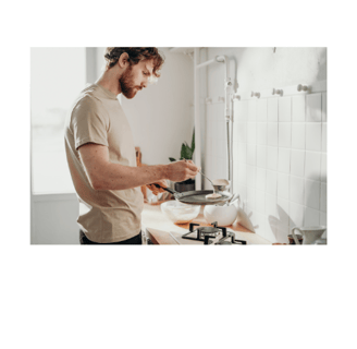 a man in a tan shirt is making pancakes in a kitchen