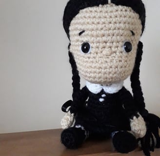 Amigurumi character doll in the style of Wednesday Adams. Crocheted goth doll.