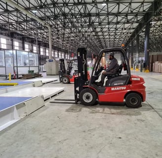 a forklift truck in a warehouse with a man in the background