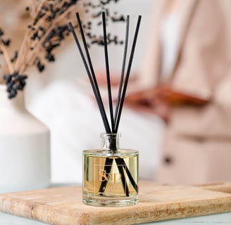 a glass bottle of home scent with a wooden board on a table